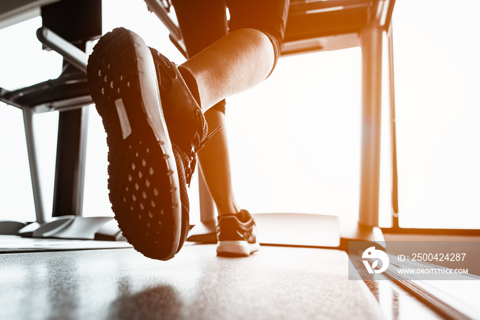 特写鞋子，女性在健身房跑步机上跑步。锻炼概念。健身和健康生活