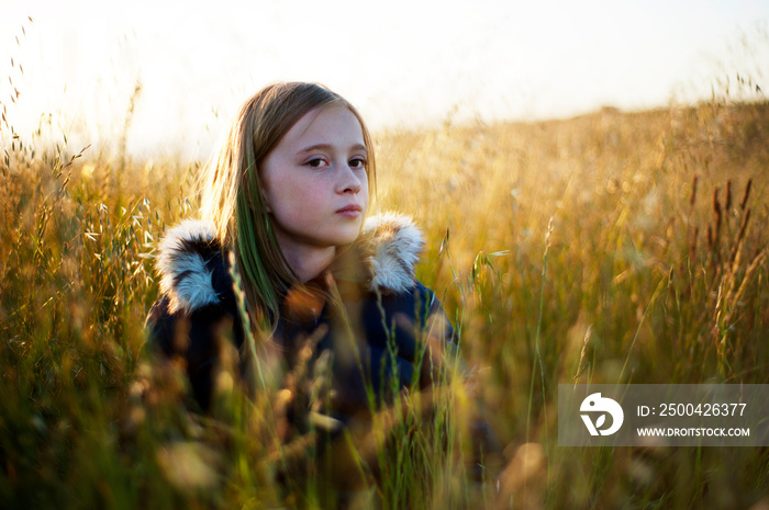 Girl (10-11) sitting in wheat field