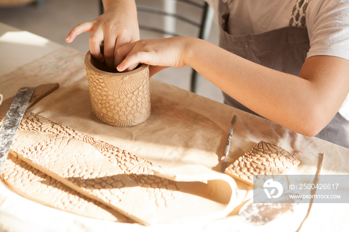 Cropped shot of unrecognizable child making ceramic mug at pottery class