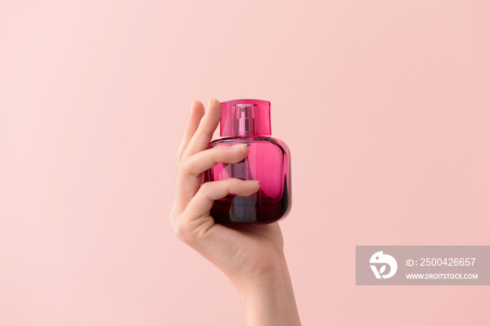 Woman holding bottle of perfume on color background