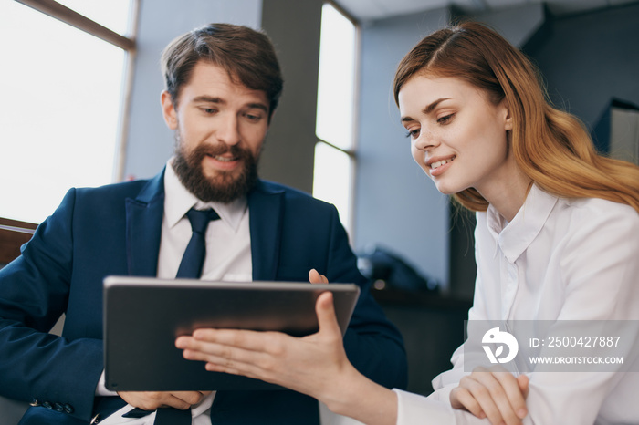 man and woman in business suits looking at the tablet managers professionals