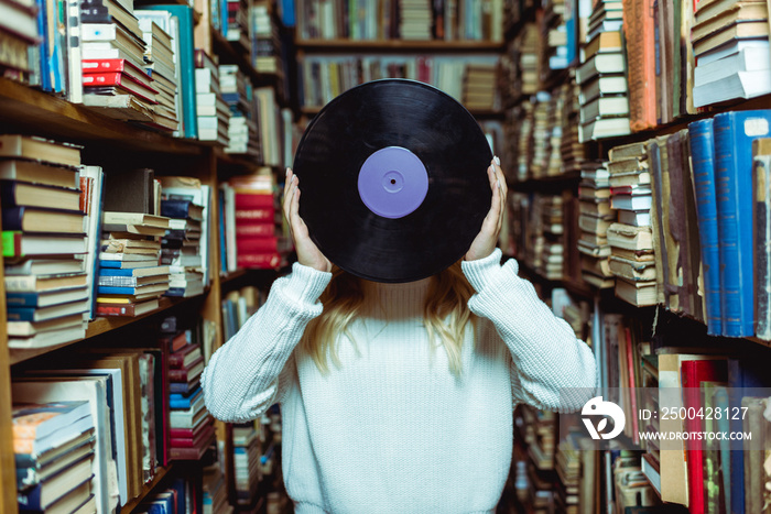 cropped view of young adult woman holding vinyl in library