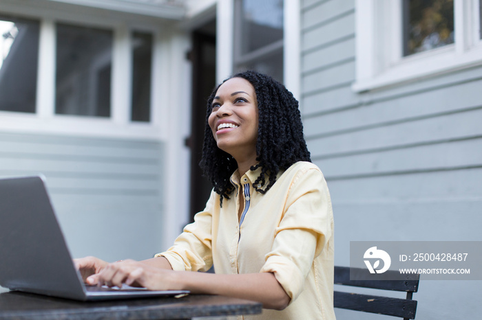 Smiling young woman using laptop on patio