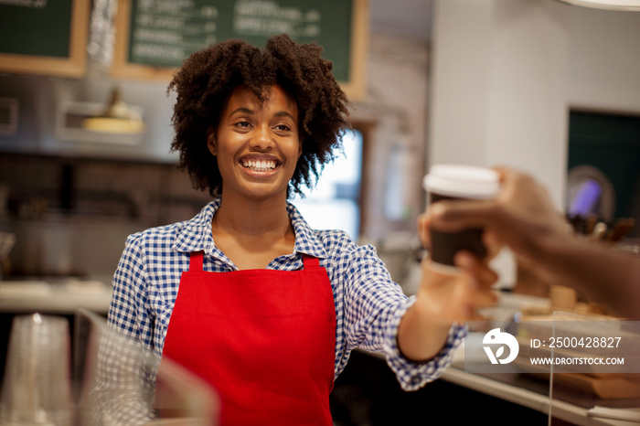 Cropped hand of male customer buying coffee from female barista at counter in cafe