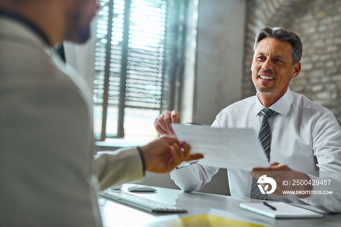 Happy businessman taking resume from a candidate during job interview.