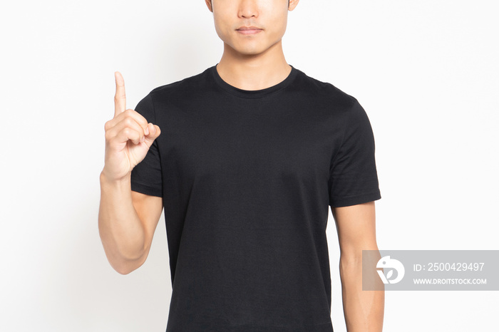 白い背景の前に立ってポイントを示す黒いTシャツを着ている若い男性