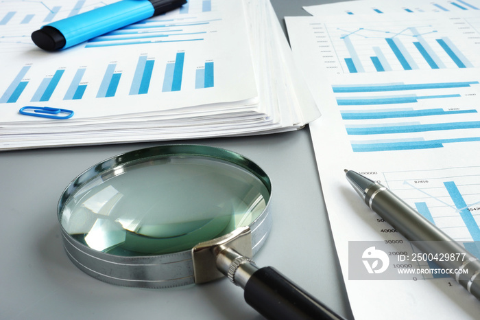 Magnifying glass and business report for auditing.