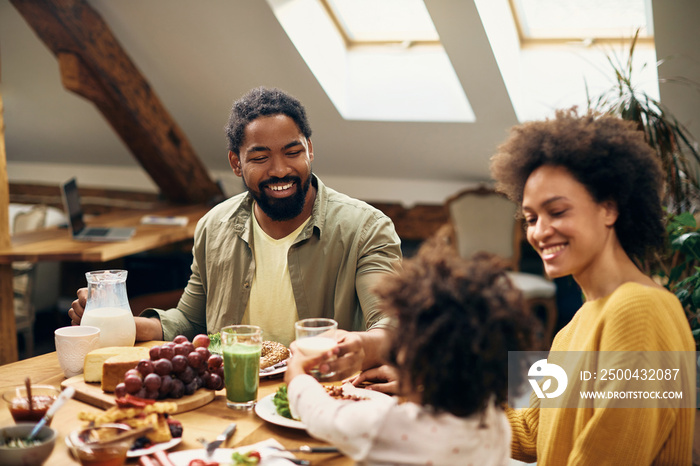 快乐的黑人家庭在家里的餐桌上享用早餐。