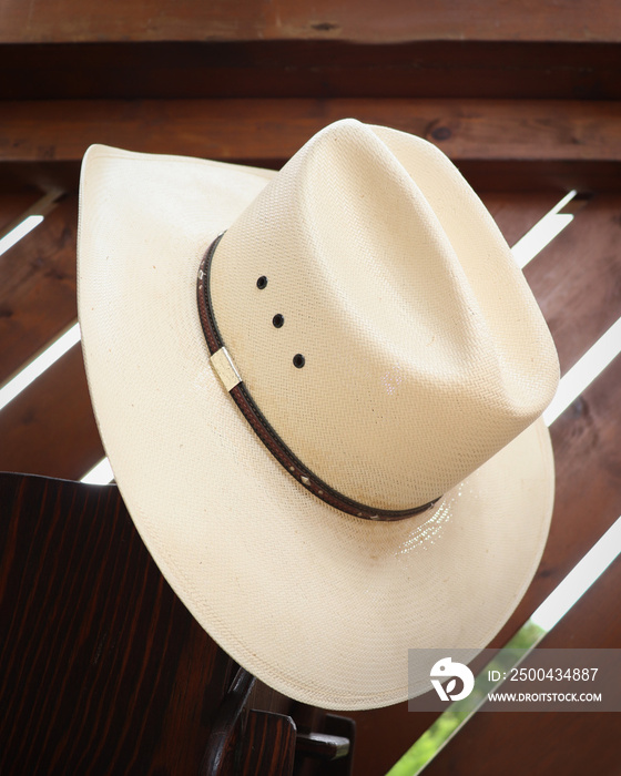 Large white straw cowboy hat with a band hanging.