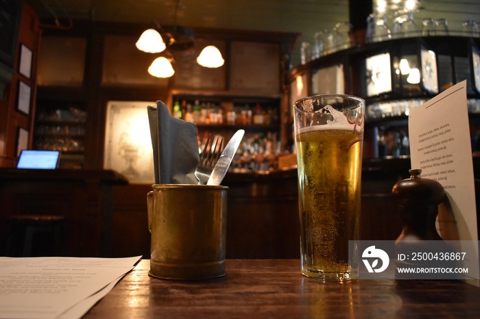 Glass full of beer on a traditional pub table. Place without customers