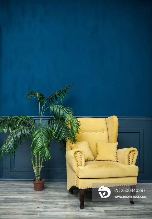 蓝色墙壁上的时尚黄色椅子。