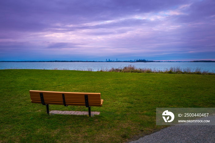 引人注目的紫色云景和公园里的空长椅。Nut i绿色上空的黄昏海景