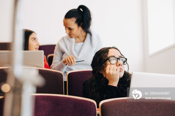 Thoughtful student with laptop in classroom at university