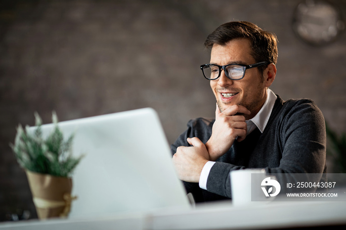 Happy entrepreneur using laptop and reading an e-mail at work.