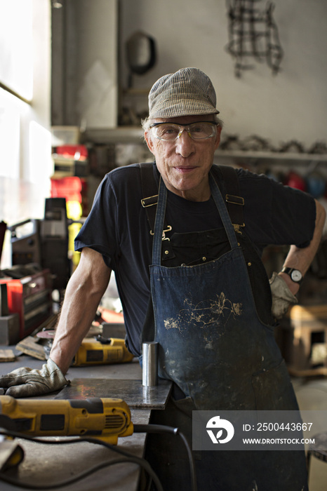 Portrait of senior man with hand on hip standing in workshop