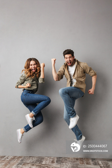 一对快乐的年轻夫妇跳跃的全长肖像