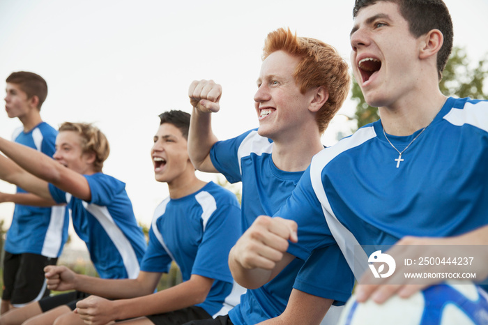 Soccer team cheering from bench.