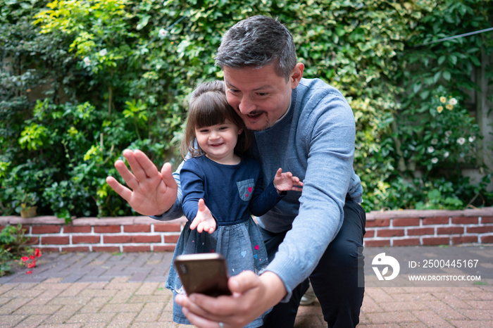 Smiling man with daughter having video call outdoors