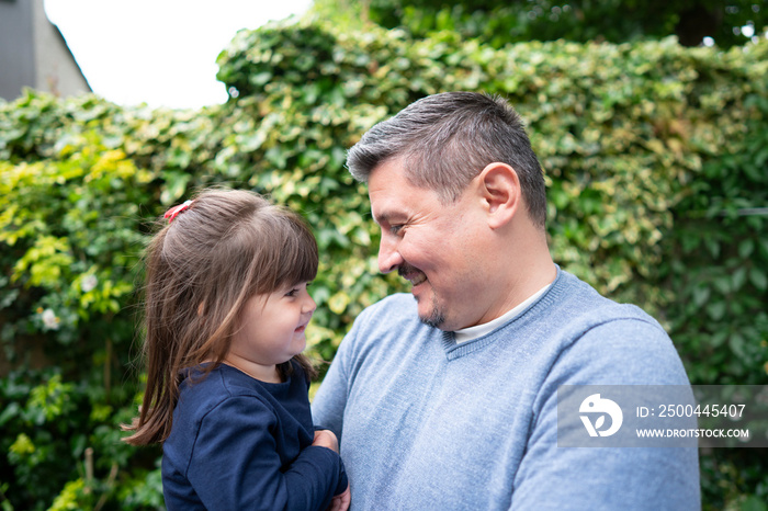 Smiling man holding daughter outdoors