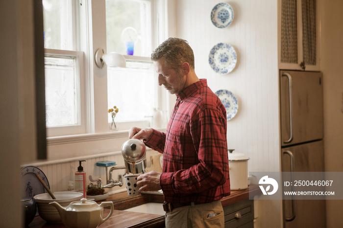 Side view of man pouring tea into cup at home