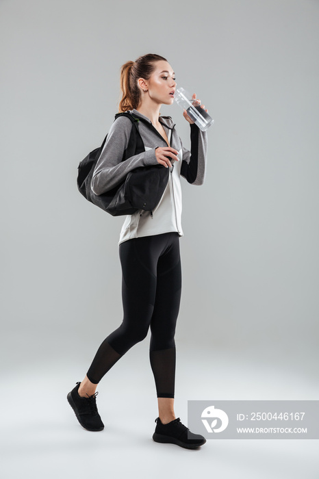 年轻漂亮的健身女士提着运动包喝水