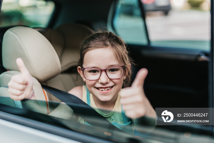 Cute girl sitting in a car on a safety child car seat.