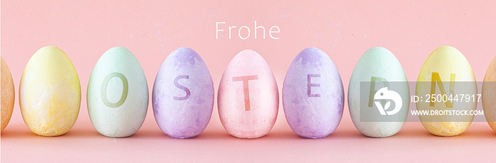 Pastellfarbene Ostereier stehen in einer Reihe nebeneinander. Osterdekoration auf pink- farbigem Hin