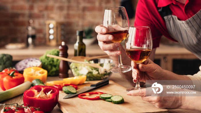 Loving seniors clinking glasses with wine at kitchen