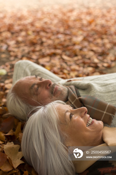 Happy senior couple laying in autumn leaves