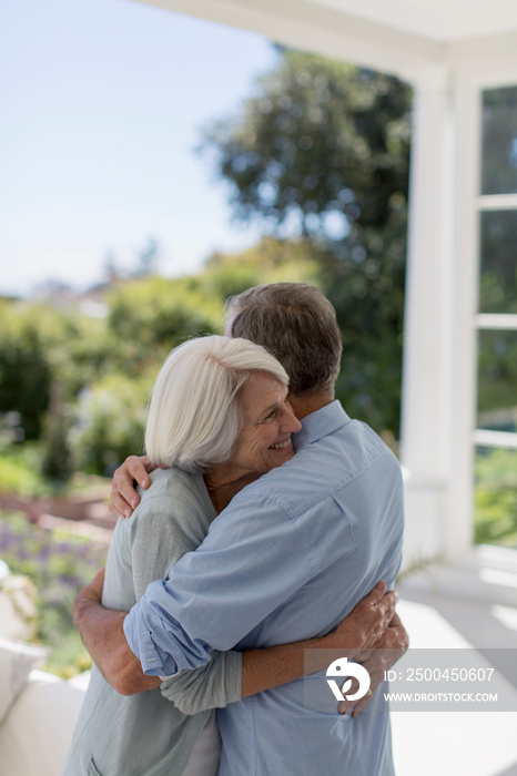 Affectionate senior couple hugging on sunny patio