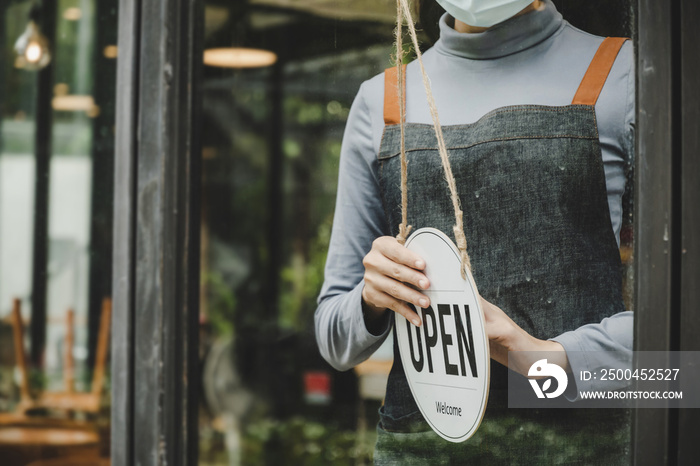 Open. waitress staff wearing protection face mask, apron turning open sign board on glass door in mo