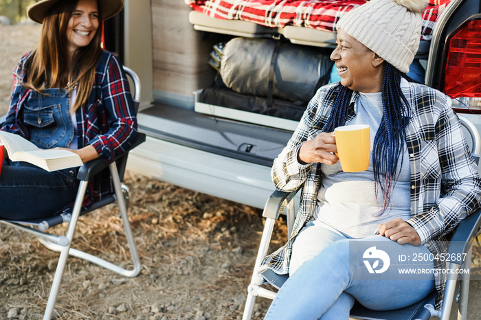 多种族女性朋友在户外喝咖啡的同时，与露营车一起露营，玩得很开心-旅行