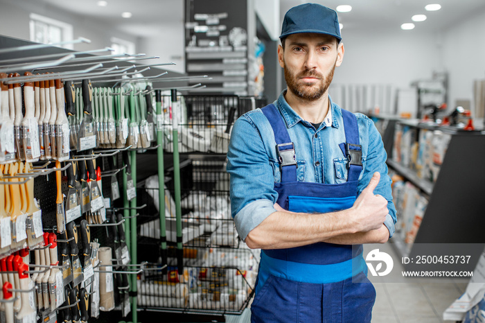 Portrait of a handsome man in workwear, standing between the stands with instruments for house repai