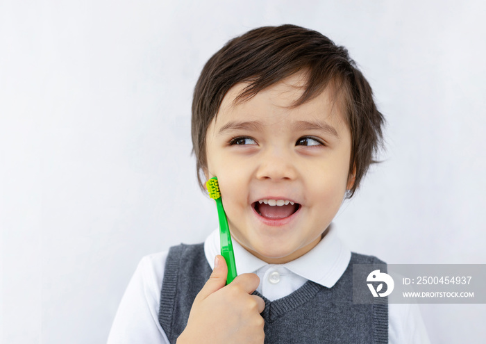 little kid smile holding toothbrush and looking out on white background, Cute child boy in school un