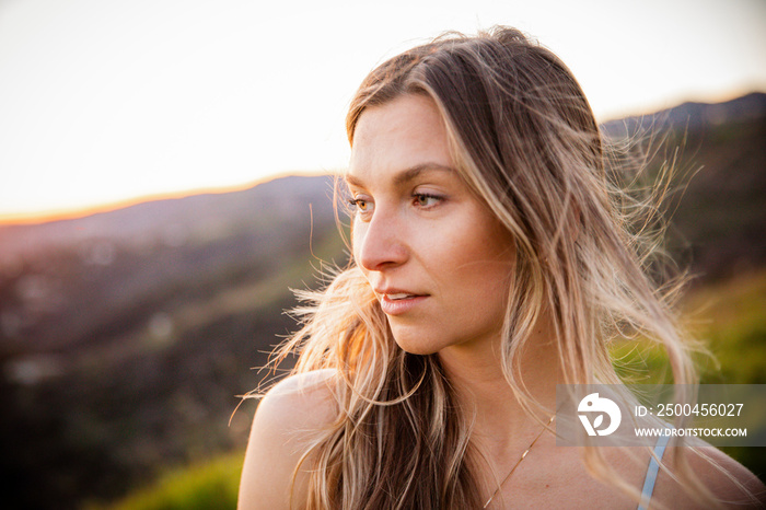 Close-up of young woman looking away against mountains