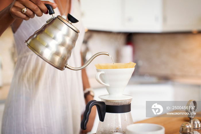 Young woman preparing coffee in kitchen