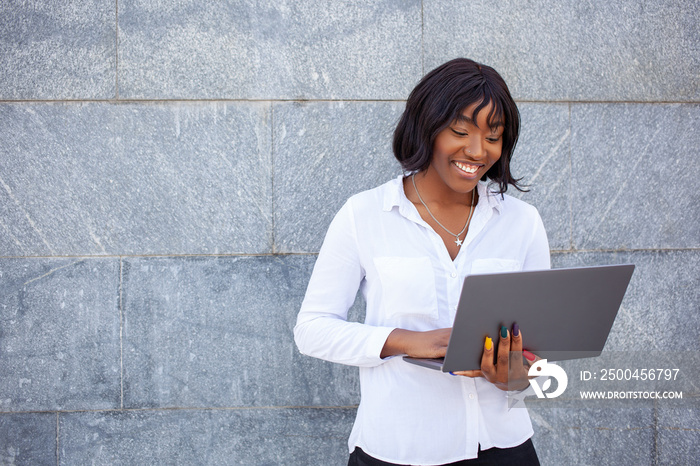 Image of optimistic African American female with happy face using laptop computer for work remotely 