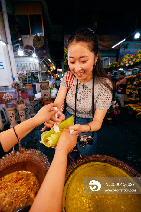 微笑的年轻女子在牙买加集市买食物