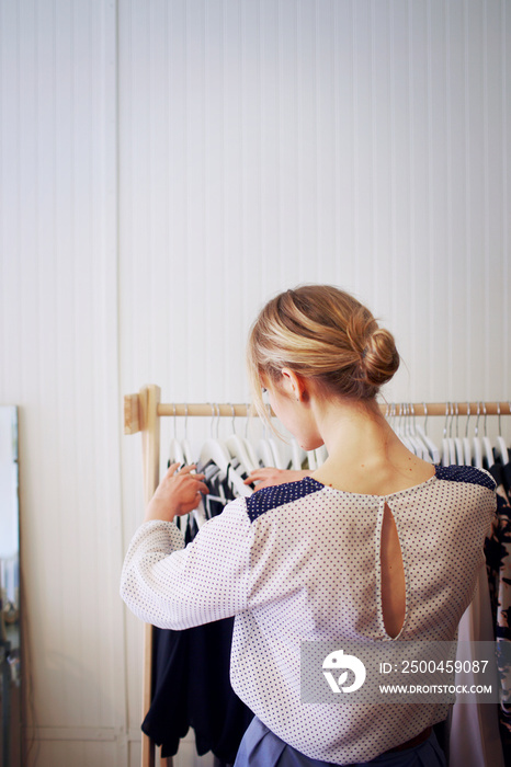 Rear view of woman arranging clothes in boutique