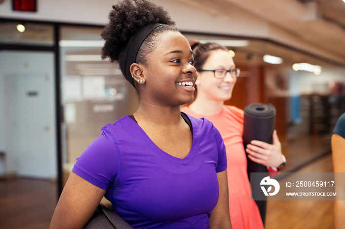 Smiling female athletes looking away while standing in yoga class