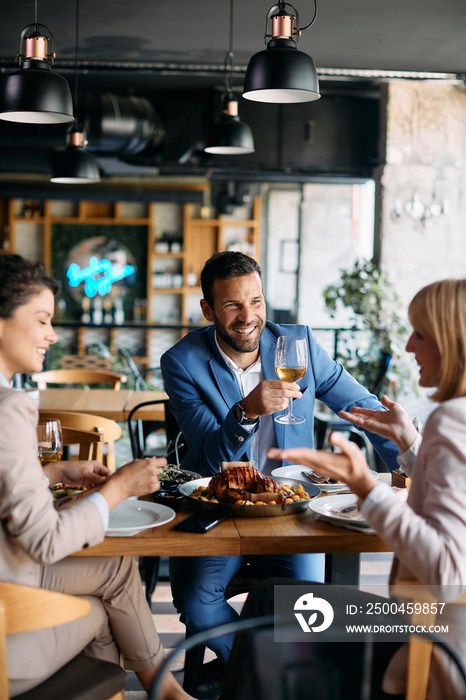 快乐的商人在餐厅与同事共进午餐时喝葡萄酒。
