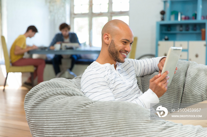 Smiling young man using digital tablet in beanbag chair