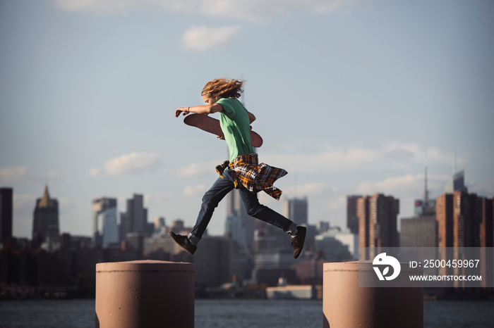 Side view of man with skateboard jumping on pillars