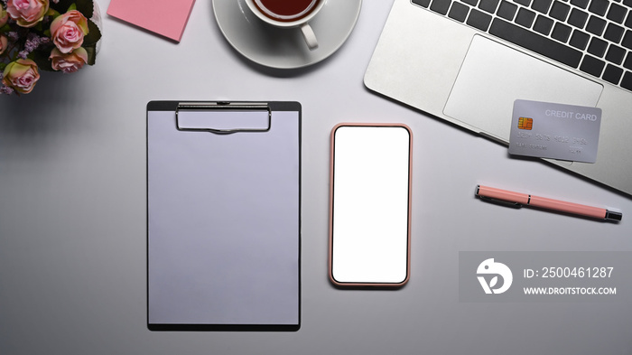 Mock up smart phone, credit card, clipboard and laptop on white table.