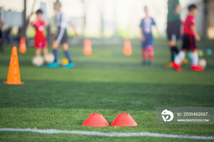 选择性关注红色标志锥是在有模糊的绿色人造草坪上的足球训练设备