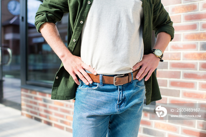 cropped shot of man in casual clothing standing with hands on hips on street