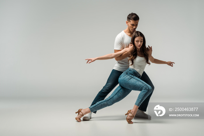 dancers in denim jeans dancing bachata on grey background