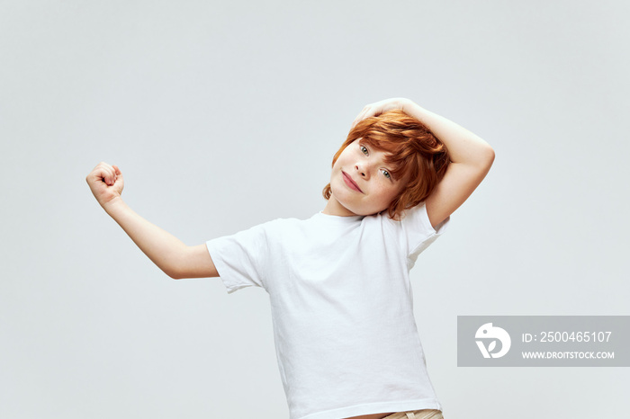 cheerful red-haired boy holding his hand on his head childhood emotions white t-shirt cropped