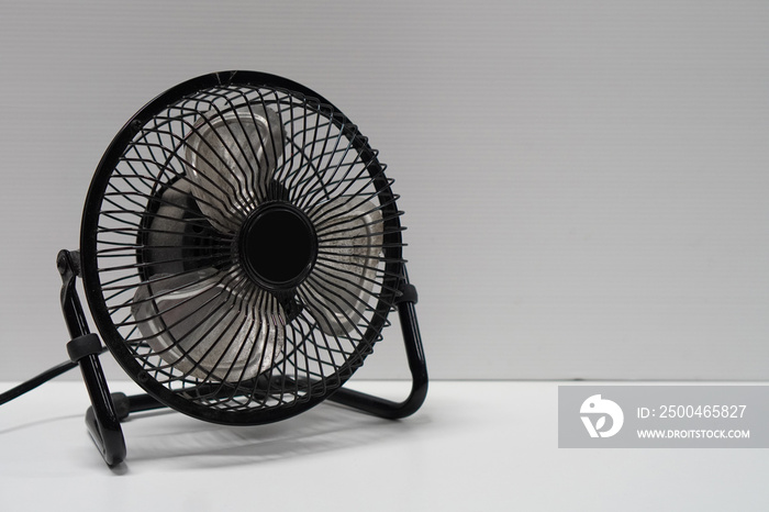 black metal table fan on white floor, white wall background, technology, object, copy space