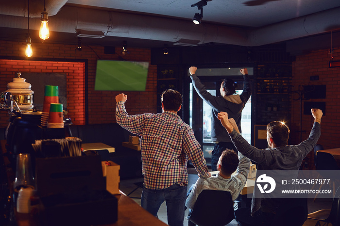 Group of happy fans are cheering for their team in sports bar.